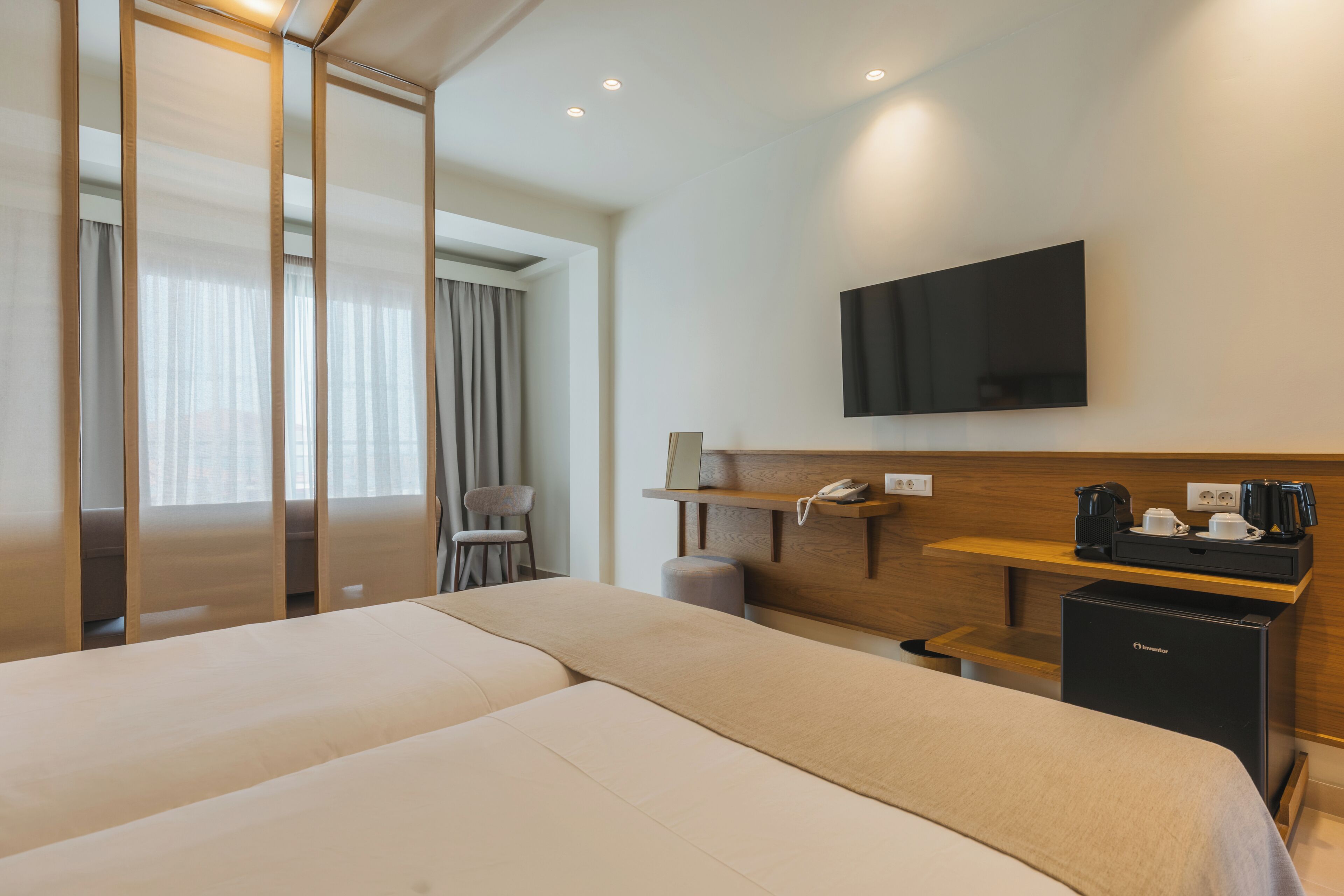 Una habitación de hotel con cama, escritorio, silla, televisor y cafetera.