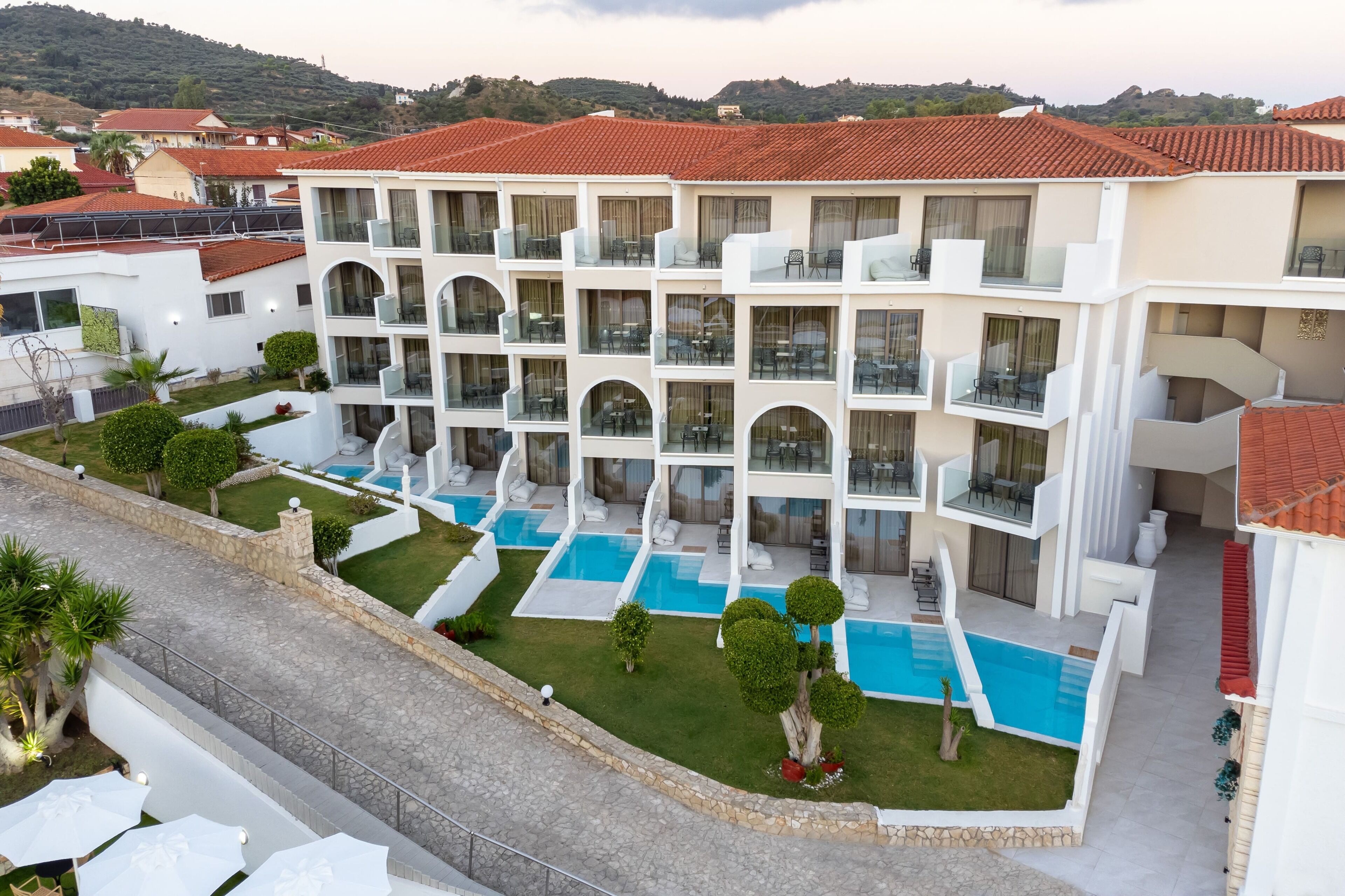 Un hôtel à plusieurs étages doté de balcons, d’une piscine et d’un jardin aménagé.