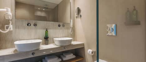 Un baño moderno con dos lavamanos, un espejo, inodoro y zona de ducha.