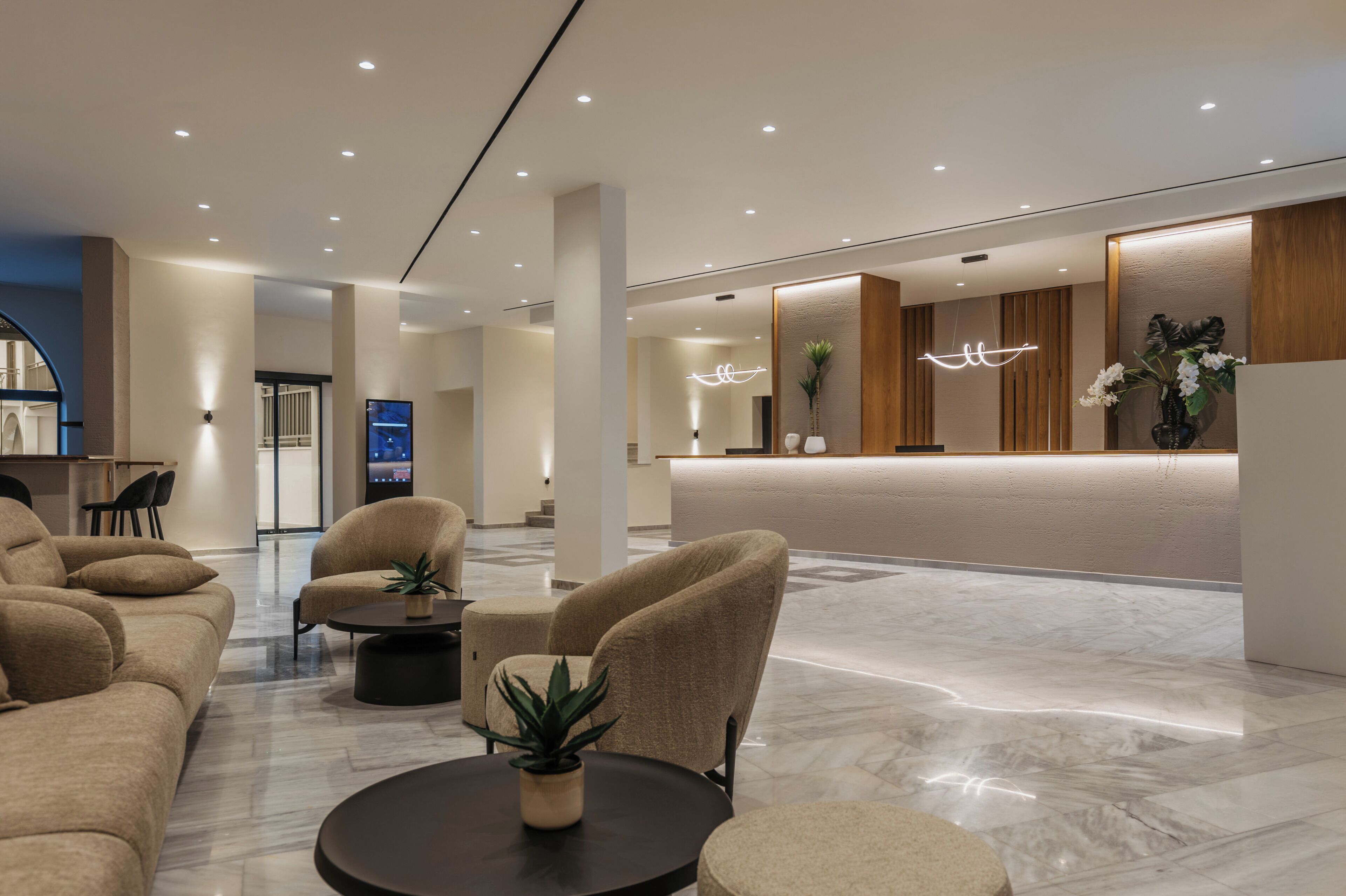 Un moderno vestíbulo de hotel con mostrador de recepción, zona de estar y un espejo grande.