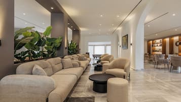 Amplia sala de estar con un sofá grande, sillones, una mesa de centro y plantas en macetas.