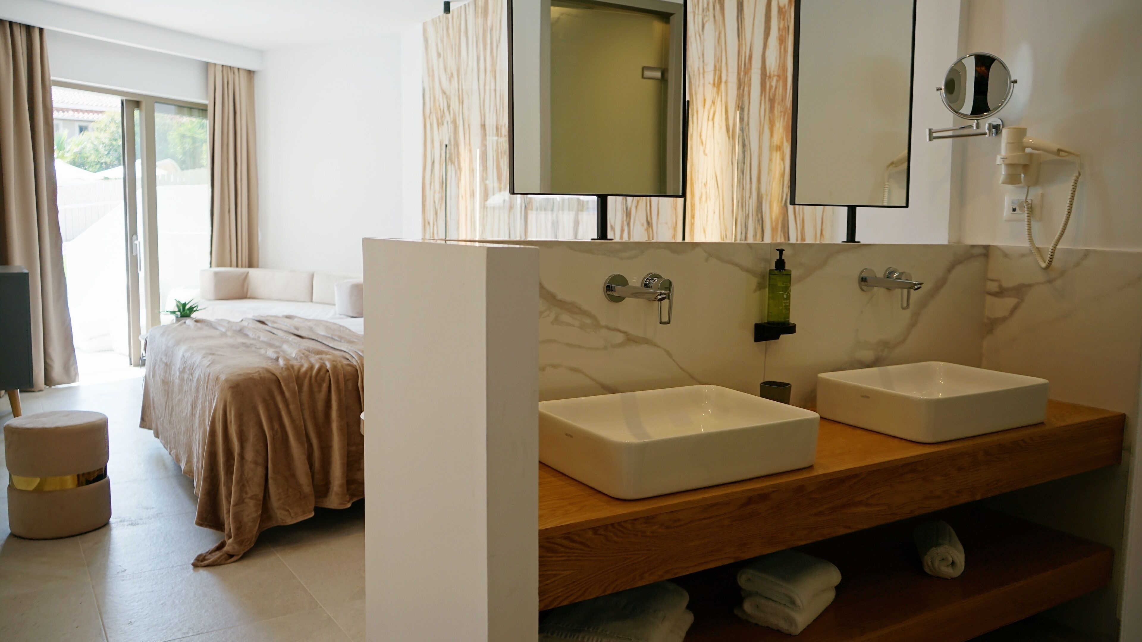 Una camera d'albergo moderna con un letto grande, due lavandini, uno specchio da trucco e una doccia.
