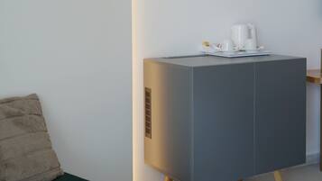 Una habitación moderna y minimalista con una consola gris, un sofá verde y una mesa redonda de madera.