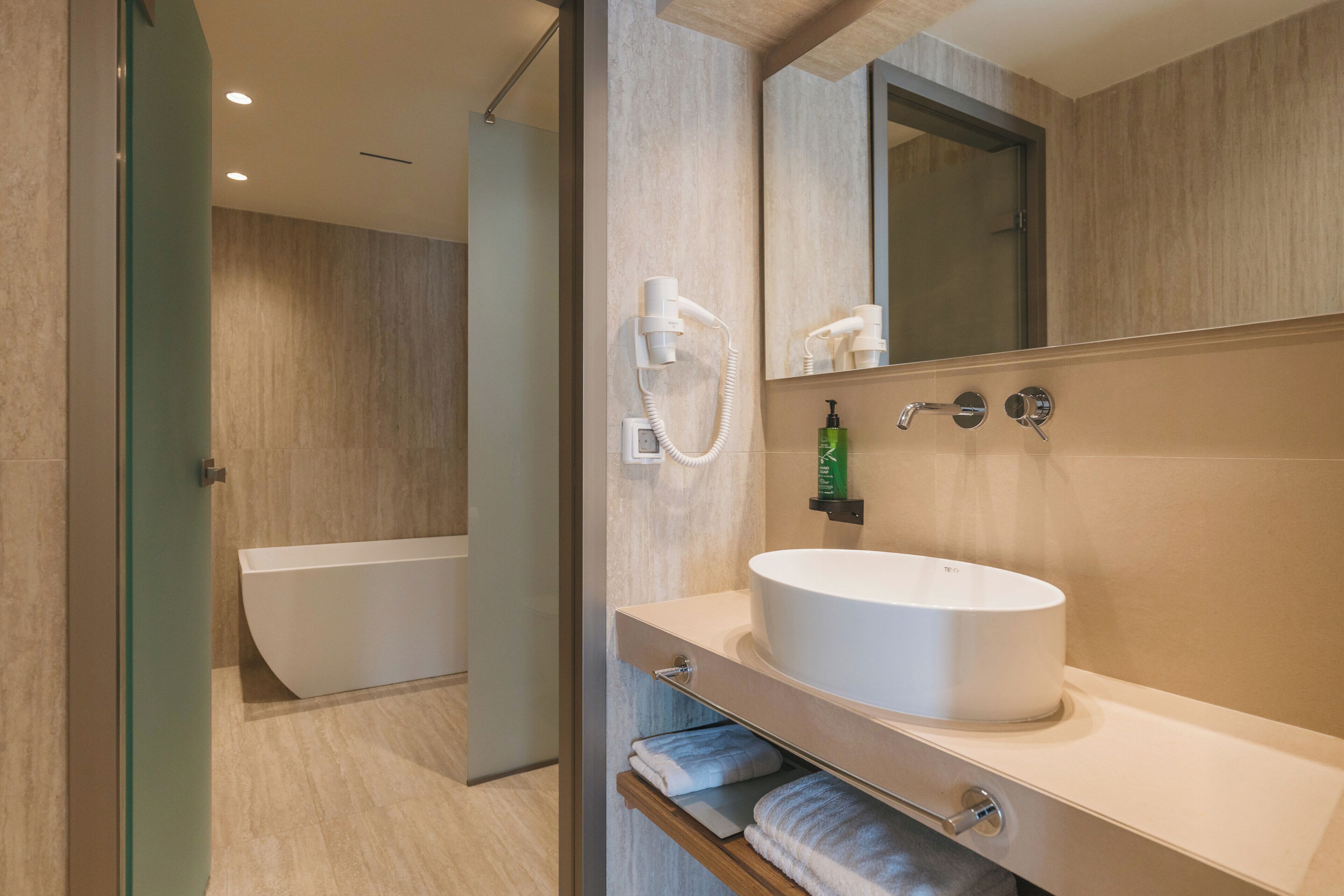 Un baño moderno con una bañera, un espejo grande y un lavabo con toallero.