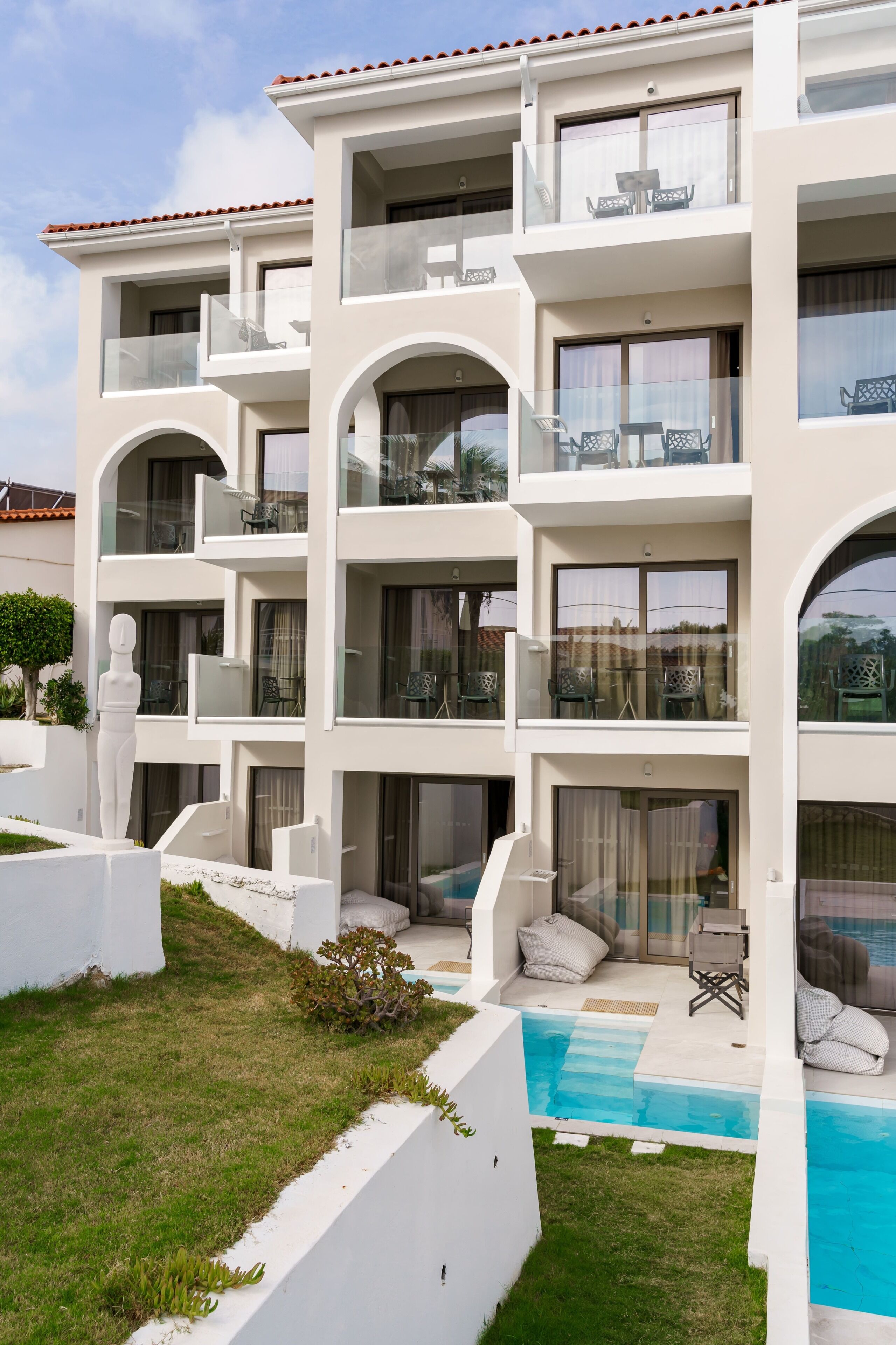 A multi-story building with balconies, a swimming pool, and outdoor seating.