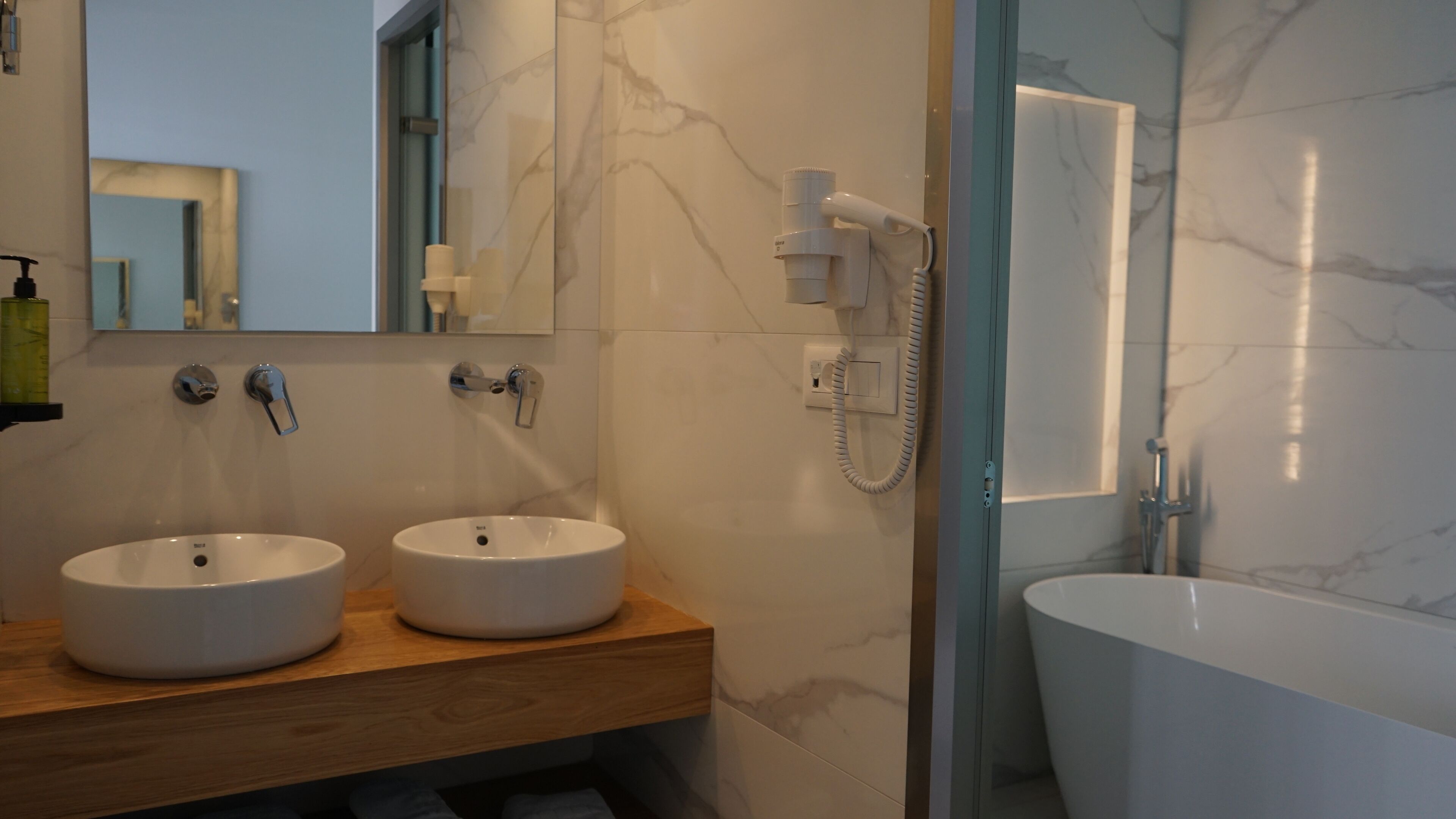 A modern bathroom with two sinks, a built-in toilet, and a separate bathtub.