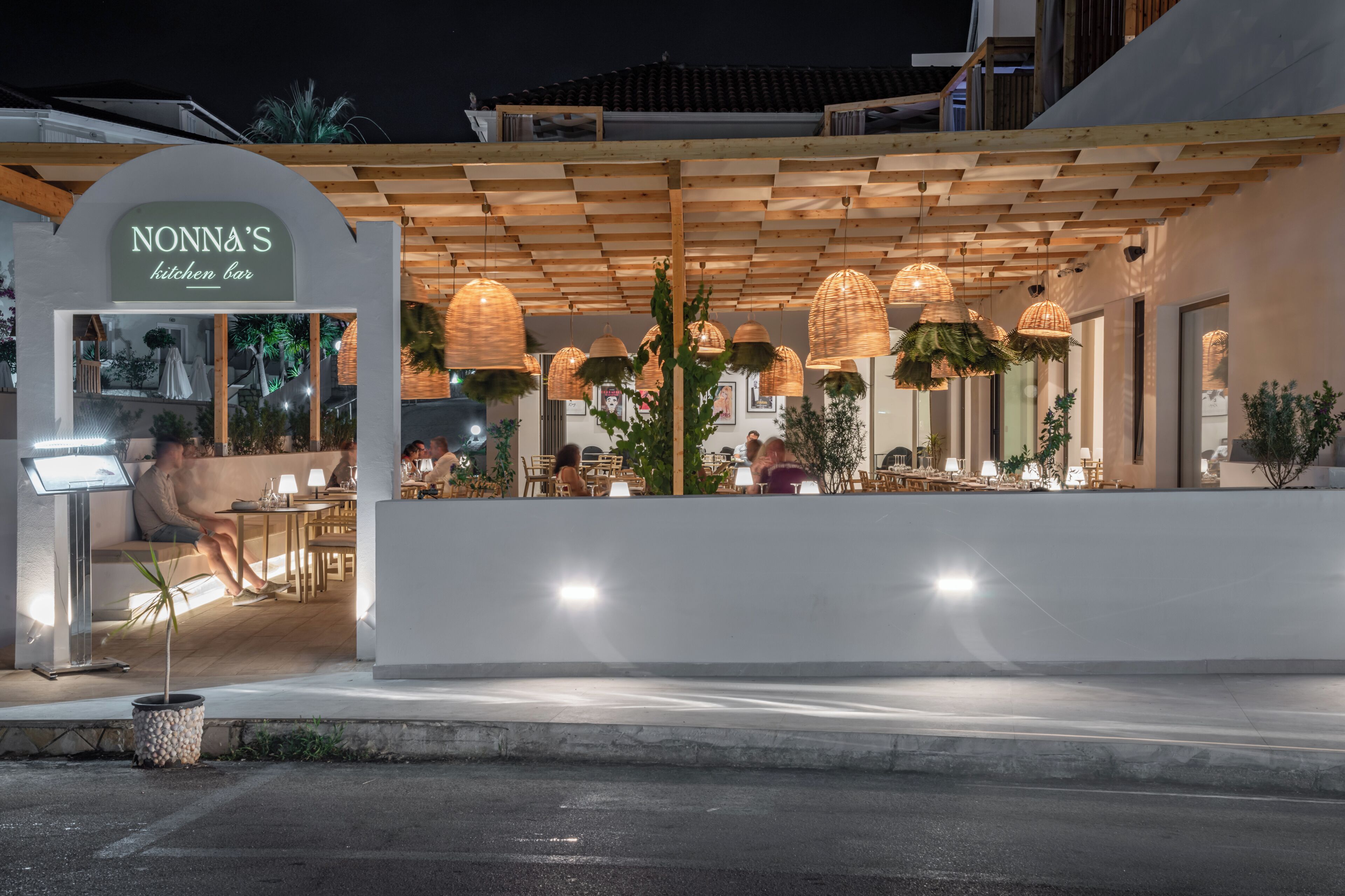 Un restaurant doté d'une pergola en bois, de lampes en osier suspendues et d'une terrasse.