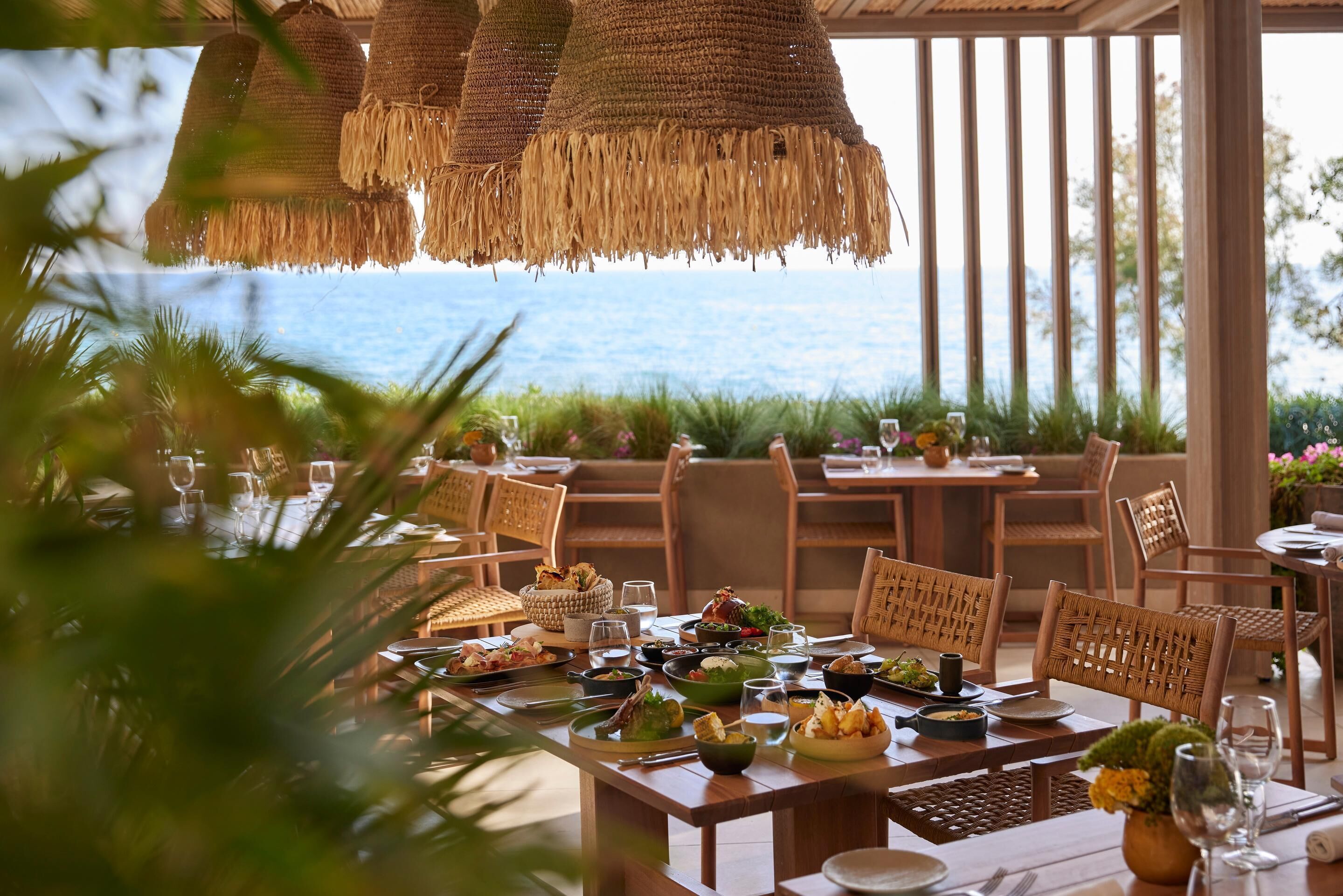 A dining area with tables set for a meal, overlooking a body of water.