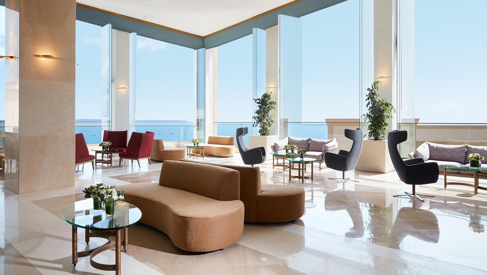 Eine großzügige Lobby mit modernem Design, die eine Mischung aus Sitzgelegenheiten und große Fenster mit Meerblick bietet.