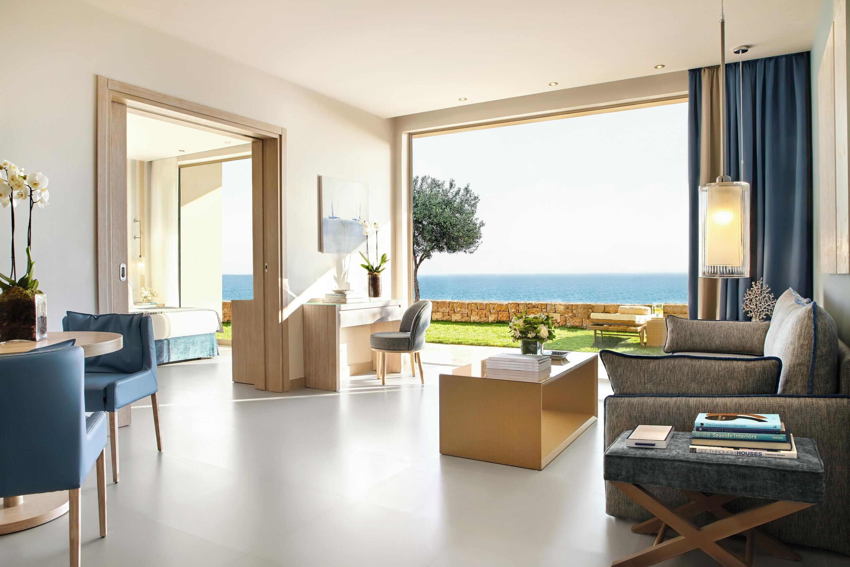 Una sala de estar moderna con vista al mar, un comedor y un espacio de descanso acogedor.