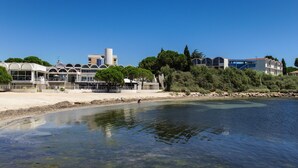 Un hotel frente al mar con vista despejada, una playa de arena y un diseño arquitectónico moderno.