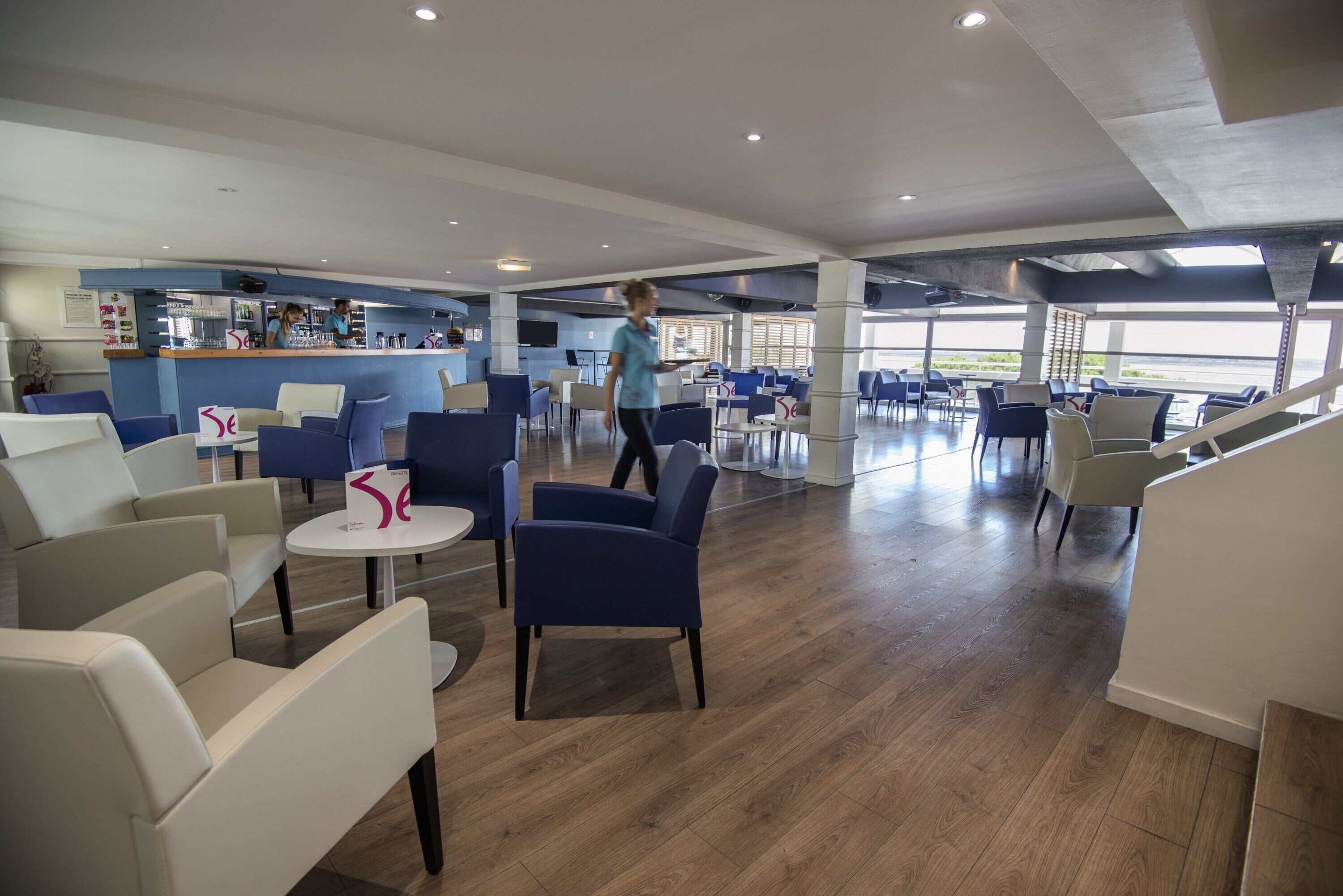 A spacious lobby with seating areas, a bar, and large windows offering views.