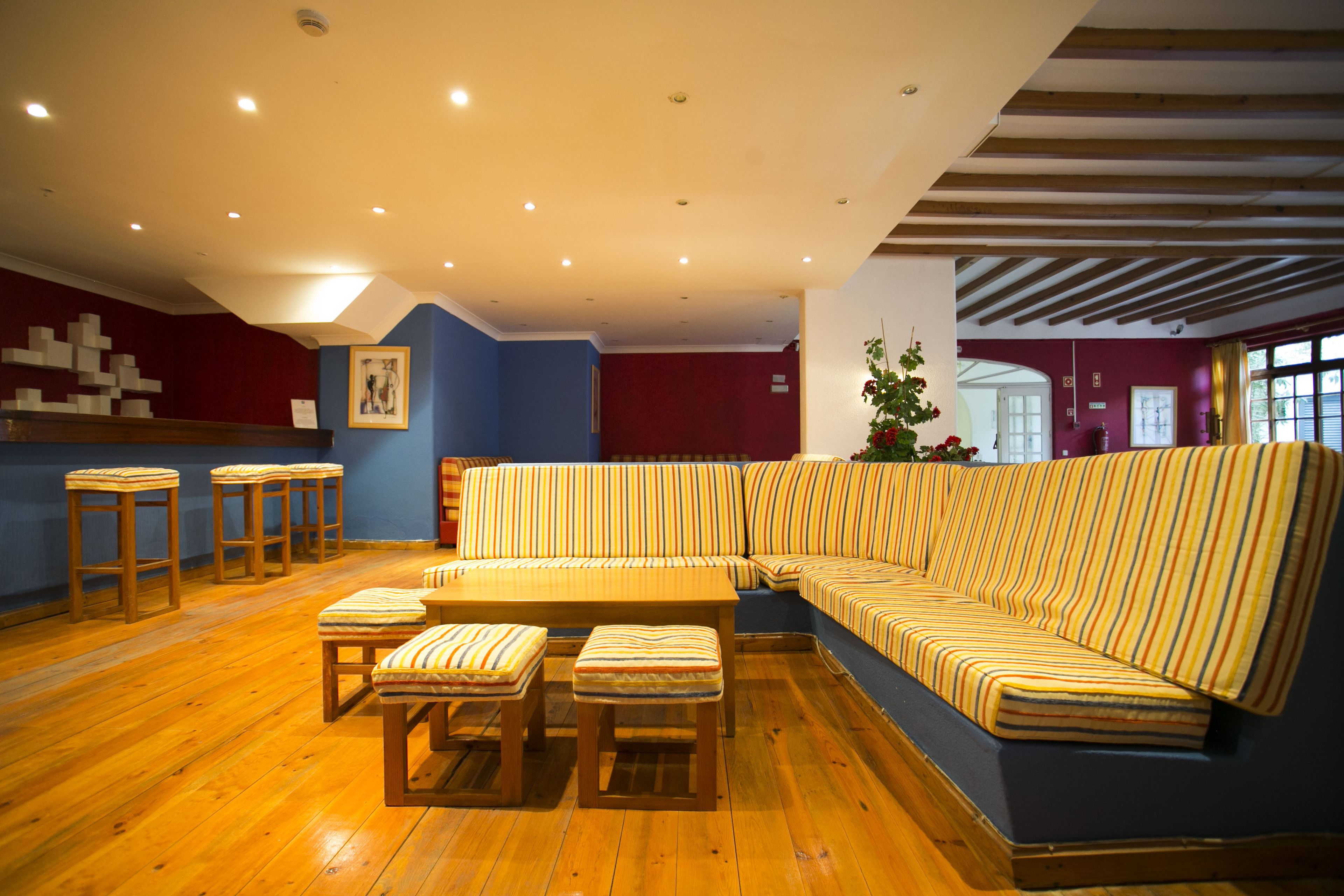 Un interior moderno con un sofá modular, taburetes de madera y piso de madera.