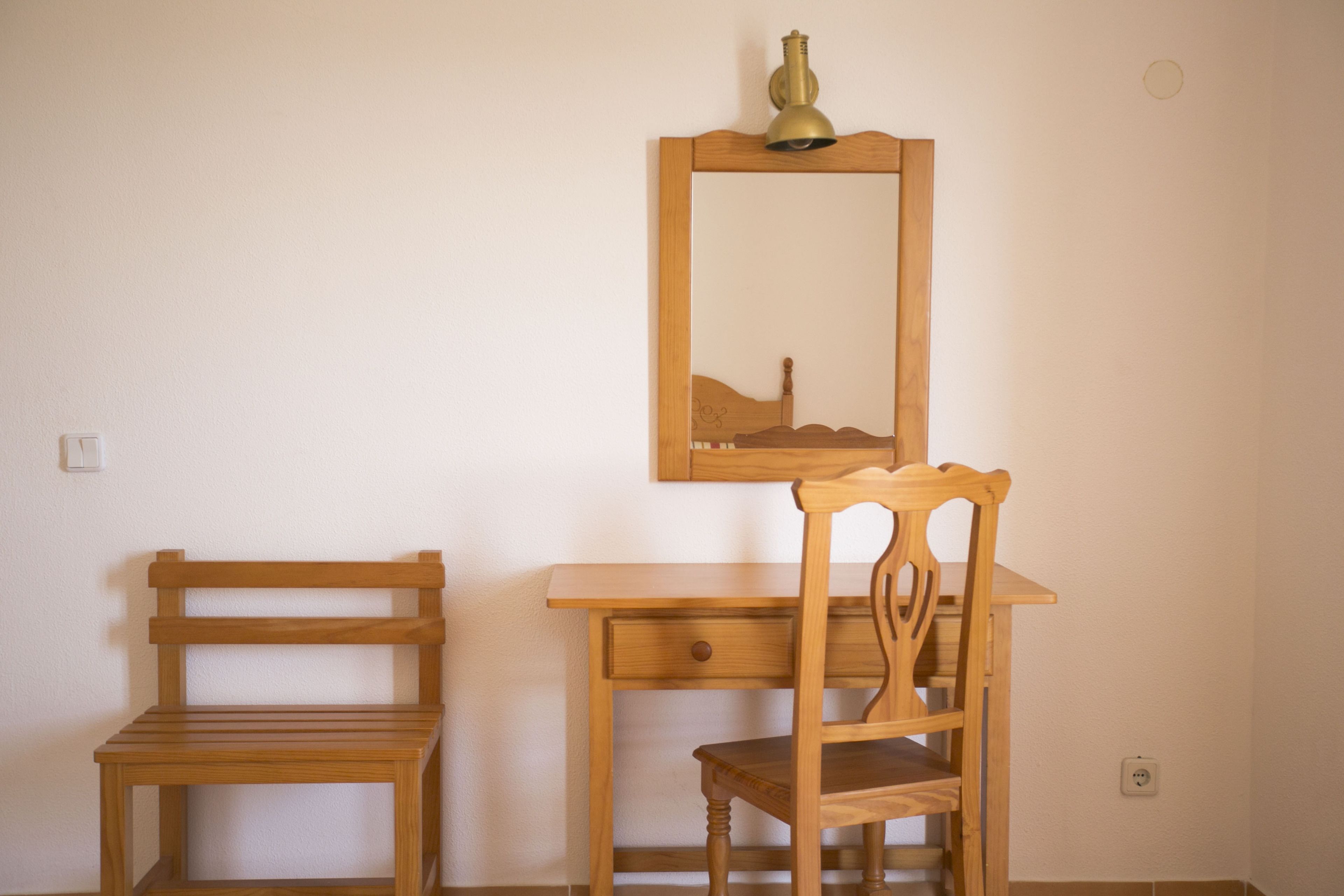 A wooden desk with a chair and a mirror.