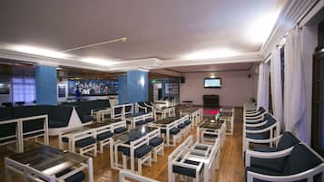 A hotel lobby with rows of seating, a bar area, and a television screen.