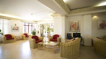 A spacious lobby with wicker furniture, a glass coffee table, and artwork on the walls.