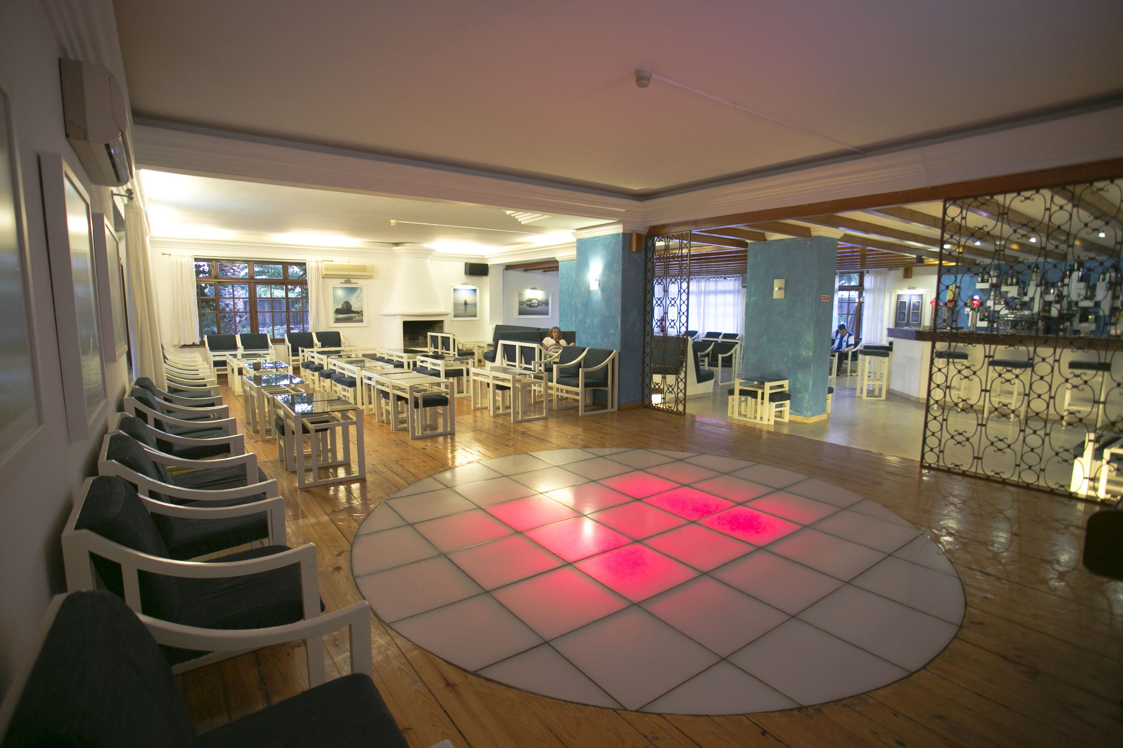 A spacious room with a circular dance floor, multiple seating areas, and a bar area.