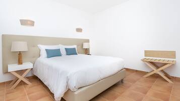 Une chambre à coucher avec un lit, deux tables de chevet et un banc en bois.
