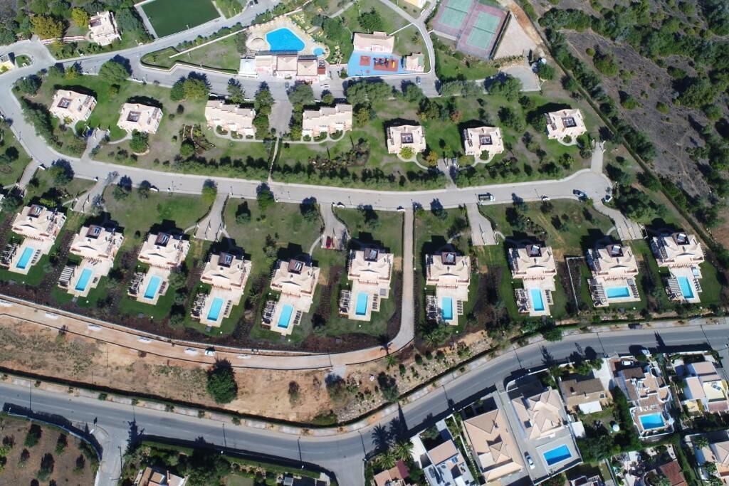 Une vue aérienne d’un quartier résidentiel avec de nombreuses maisons, des rues et une grande piscine.