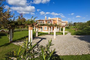 A large, two-story building with a paved driveway leading to a gated entrance. - Colina da Lapa & Villas (Lagoa)