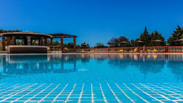 A clear blue pool with tiled flooring, a gazebo, and lounge chairs along the poolside. - Colina da Lapa & Villas (Lagoa)