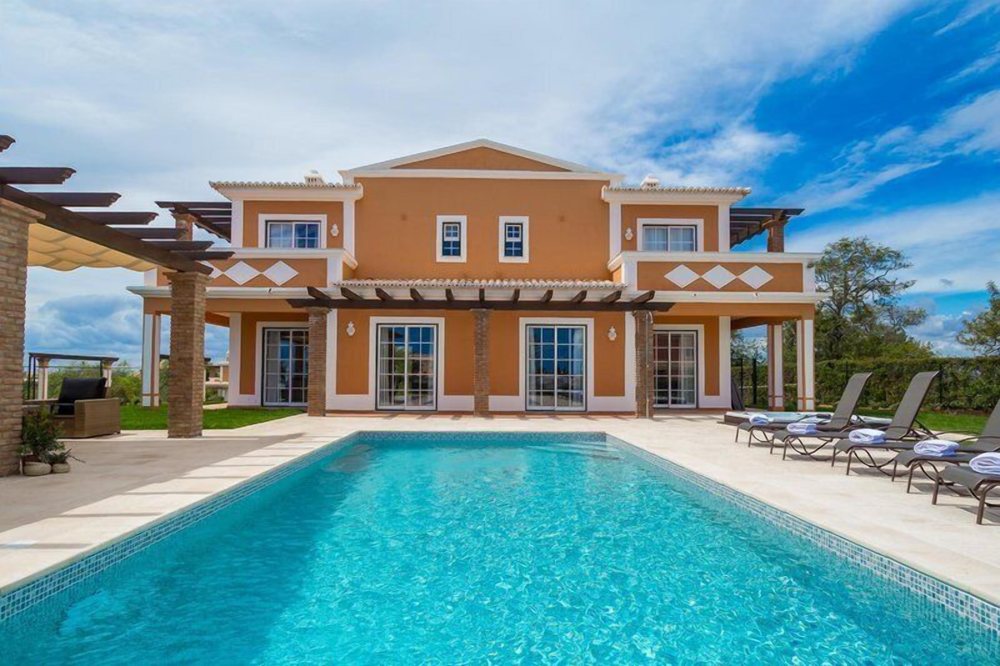A two-story house with a swimming pool in front.