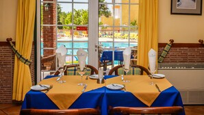 A dining table set for four with a view of a pool and a building in the background. - Colina da Lapa & Villas (Lagoa)