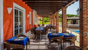 An outdoor patio with tables and chairs, a pool, and a view of a golf course. - Colina da Lapa & Villas (Lagoa)
