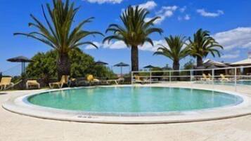 A pool area with lounge chairs and palm trees.