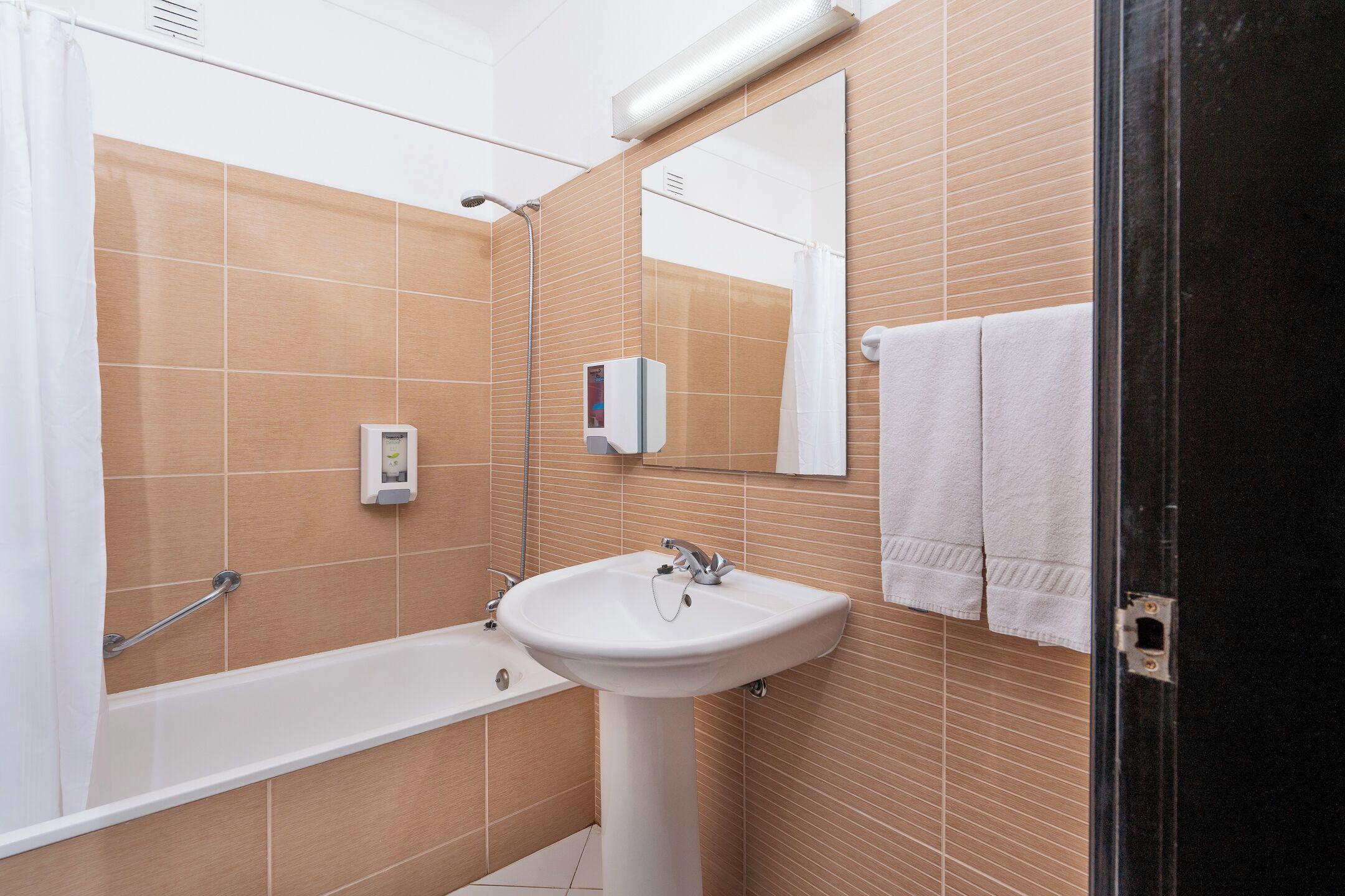 A bathroom with a bathtub, a sink, a mirror, and a towel rack.