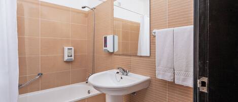 A bathroom with a bathtub, a sink, a mirror, and a towel rack.