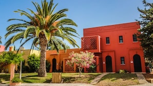 Un edificio rojo con arcos y una palmera al frente.