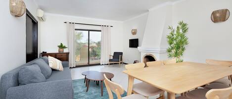 Un salon moderne comprenant un canapé, une table à manger, des chaises, un téléviseur et une cheminée.