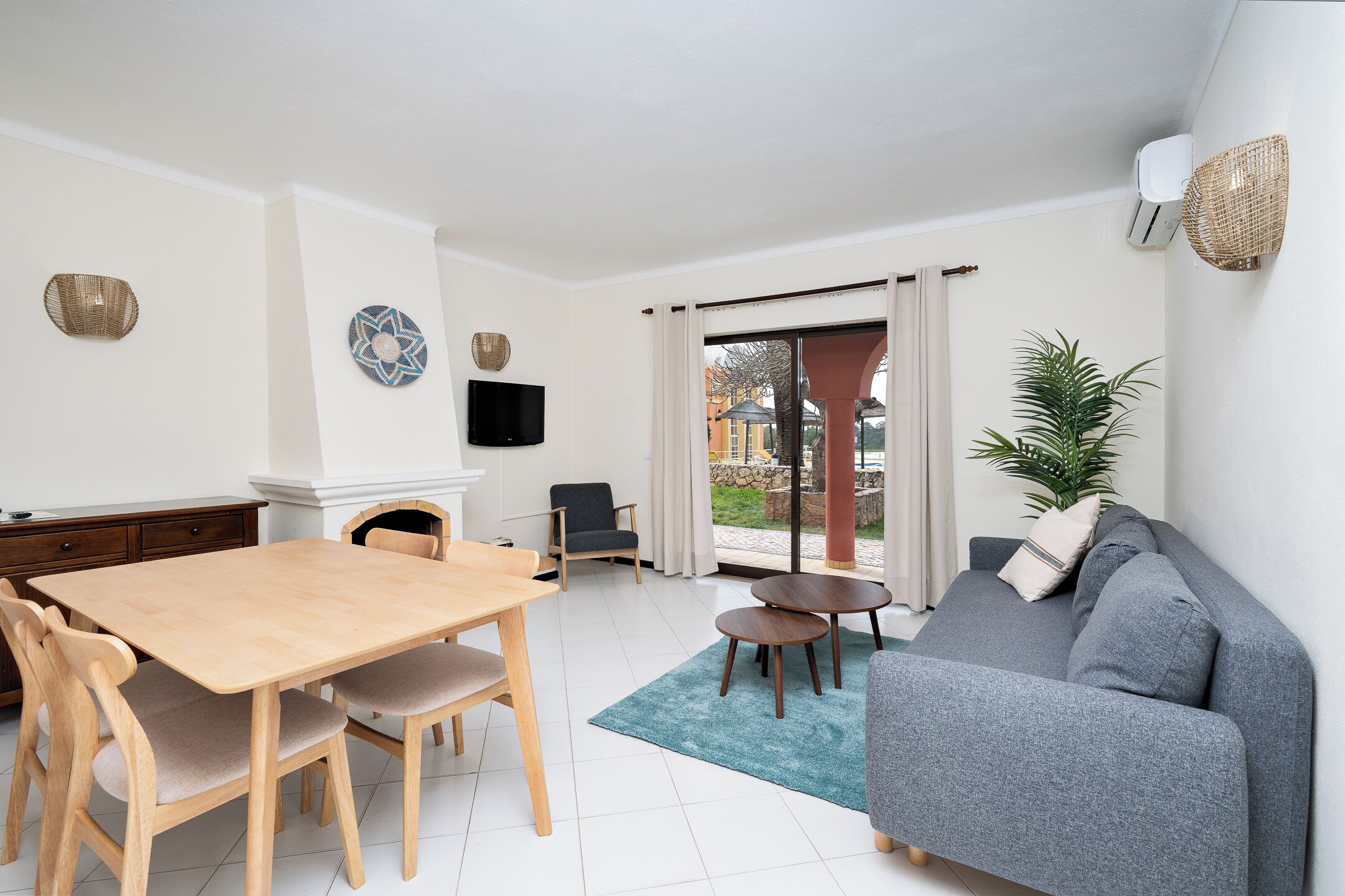 A living room with a sofa, a dining table with chairs, a TV, and a fireplace.