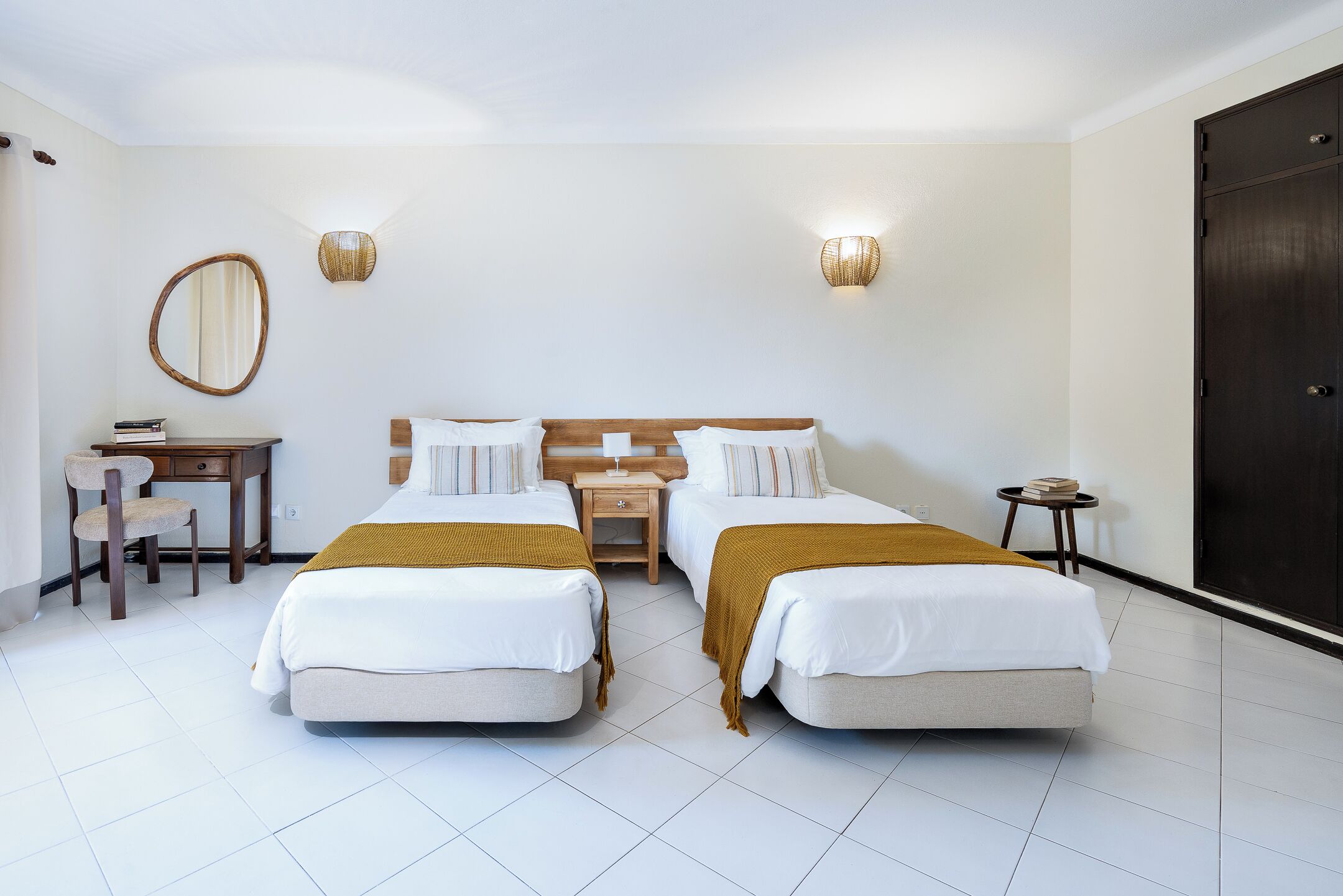 Hotellihuone, jossa on kaksi sänkyä, työpöytä, tuoli ja vaatekaappi.