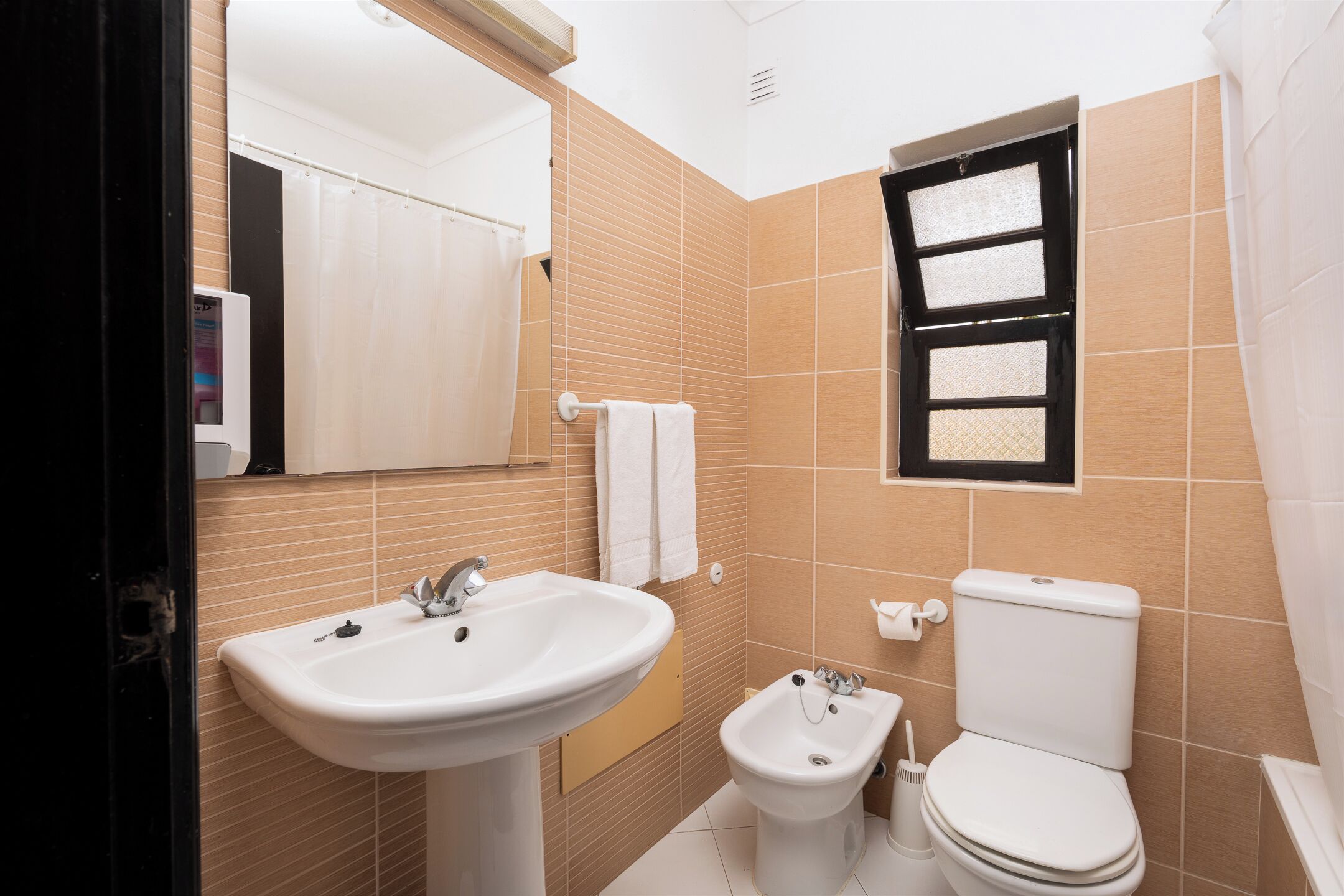 Ein Badezimmer mit Waschbecken, Bidet, Toilette und Spiegel.