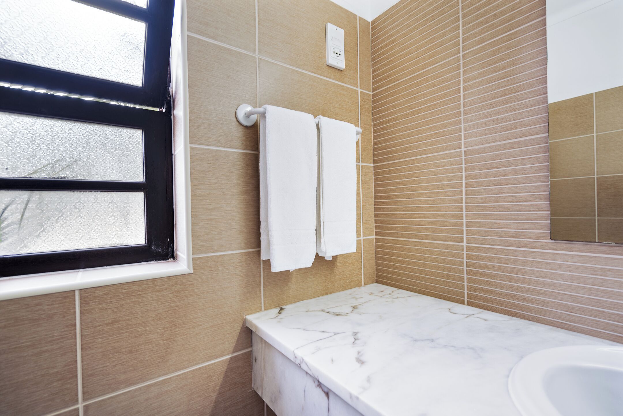 A bathroom with a marble countertop, a sink, and a towel rack with two towels.