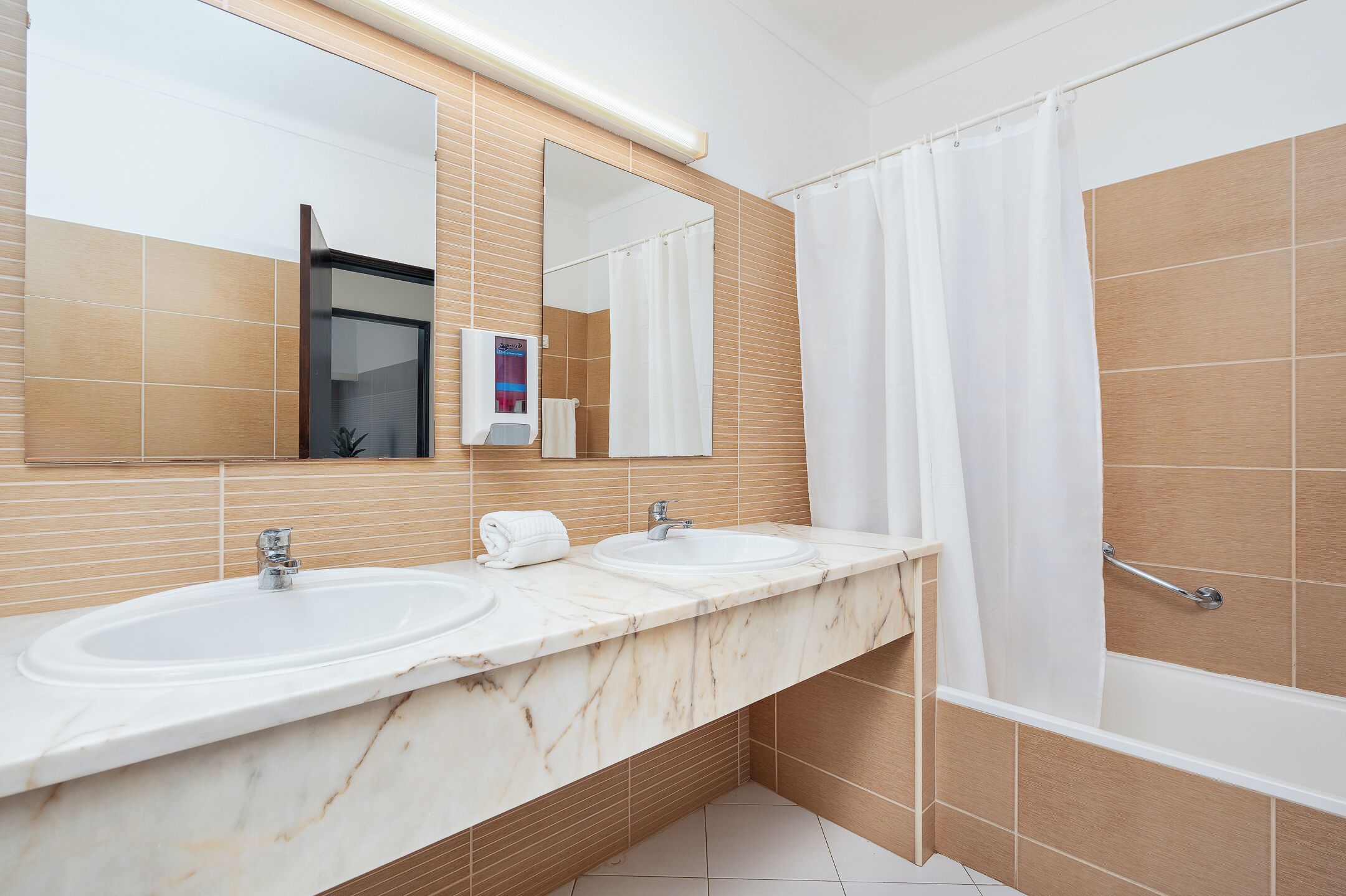 A bathroom with two sinks, a mirror, a shower curtain, and a towel rack.