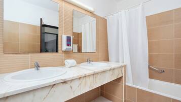 Een badkamer met twee wastafels, een spiegel, een douchegordijn en een handdoekrek.