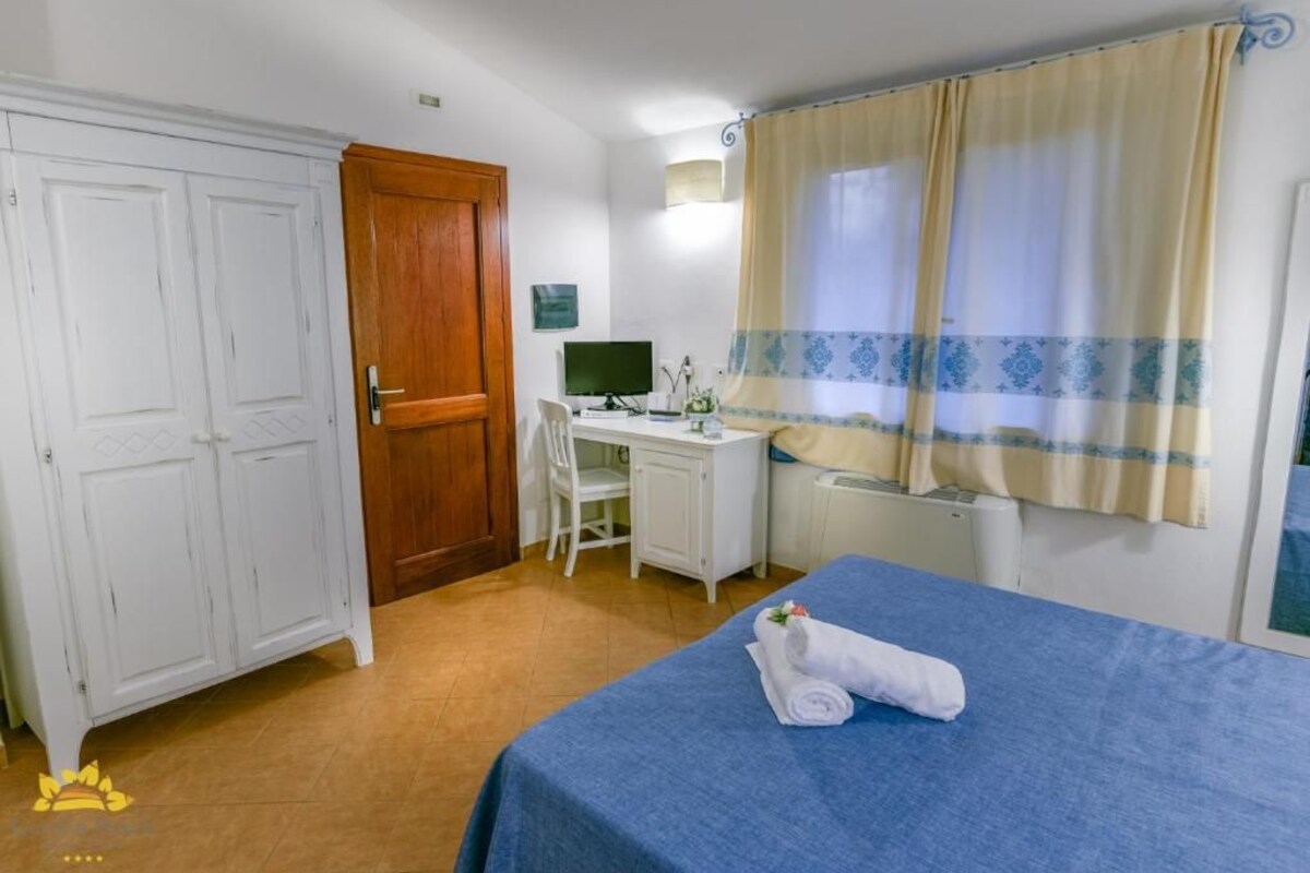 Un dormitorio con una cama, un escritorio con computadora y una silla.