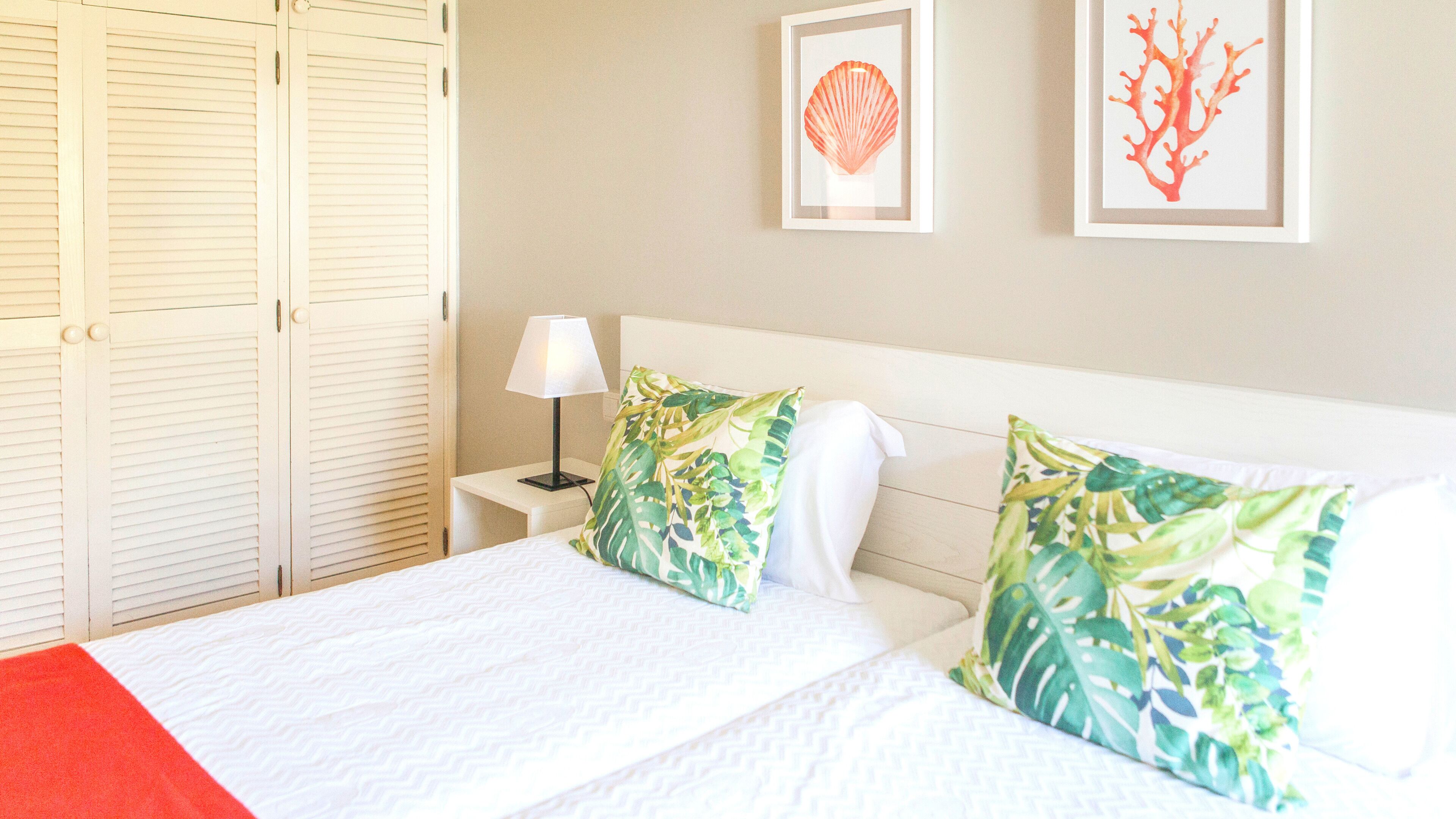 A hotel room with a bed, a nightstand, a lamp, and two framed pictures on the wall.