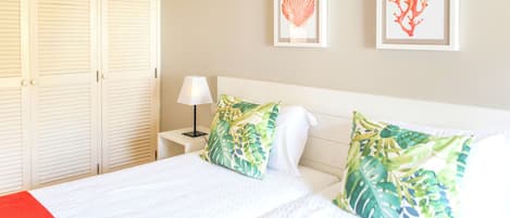 A hotel room with a bed, a nightstand, a lamp, and two framed pictures on the wall.