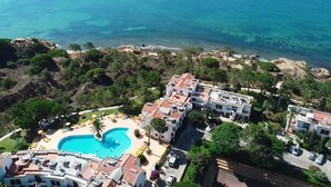 Un complexe hôtelier doté d’une piscine, situé en bord de mer et offrant une vue sur l’océan.