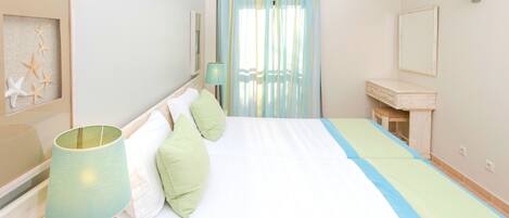 Un dormitorio con cama, mesita de noche, lámpara, cómoda y espejo montado en la pared.