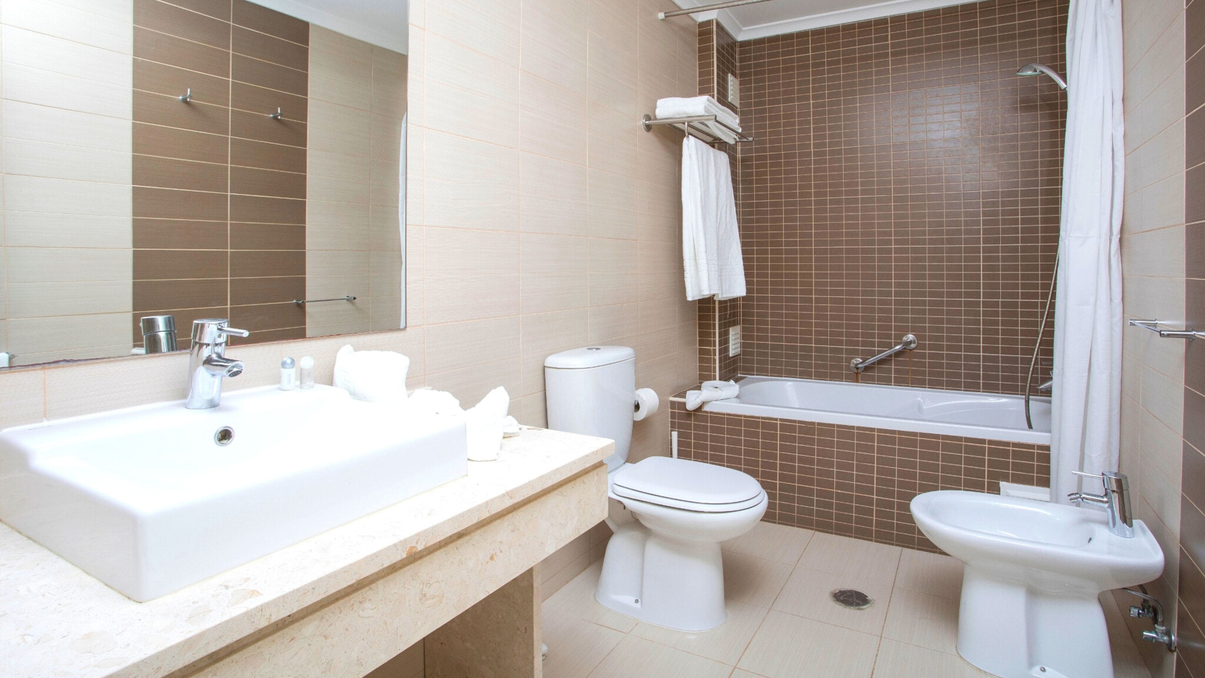 Un baño moderno con lavamanos, inodoro, bidé y bañera.