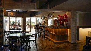 Un restaurant doté d’un bar, de tables et de chaises en bois, et d’un sol carrelé.