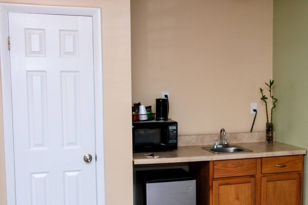 A compact kitchen with a refrigerator, microwave, sink, and wooden cabinets.