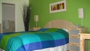 A bedroom with a bed, a nightstand, a lamp, a wall-mounted picture, and a door. - Sequoia Inn (Redwood City)