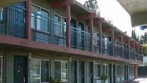 A motel with a row of rooms, each with a balcony. - Sequoia Inn (Redwood City)