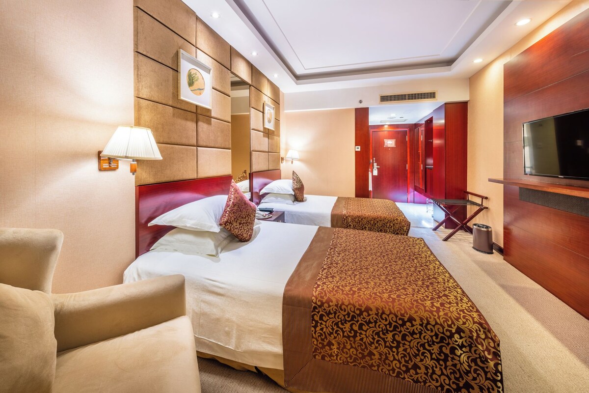Une chambre d’hôtel avec deux lits, une télévision, un bureau et une chaise.